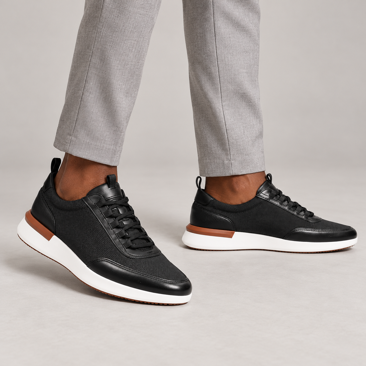 Black mesh sneakers with white soles worn with gray trousers
