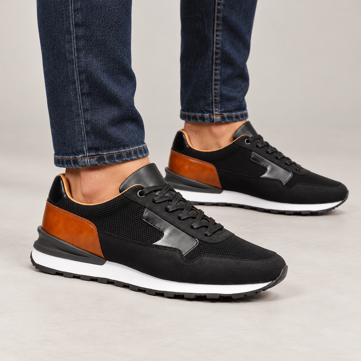 Black and cognac sneakers worn with dark blue jeans